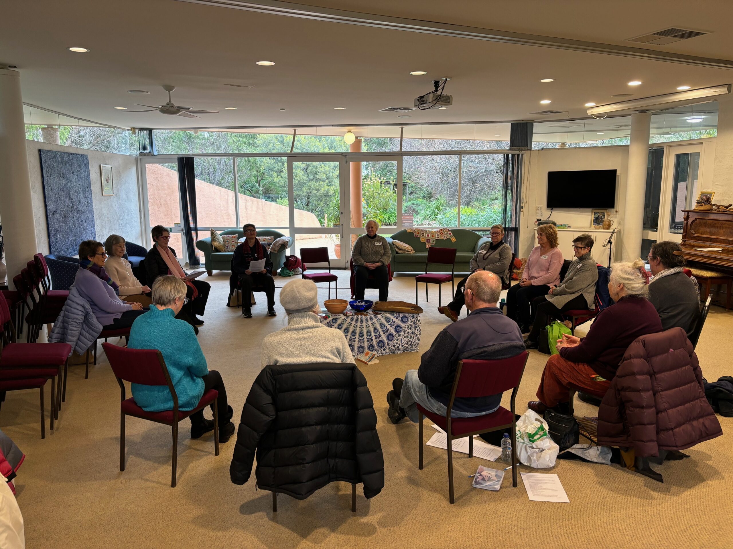 group of people indoors, sitting in a circle of chairs