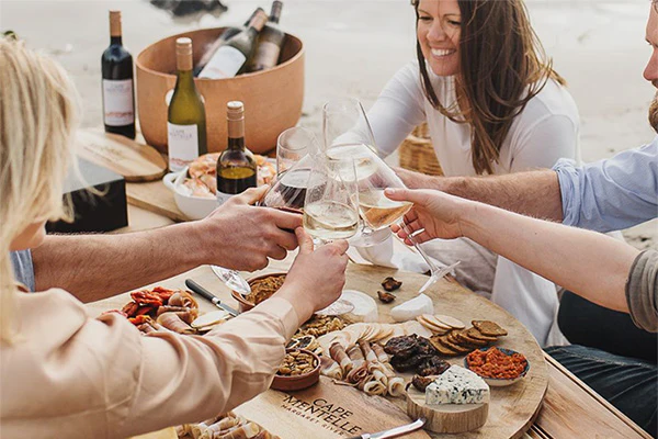 Group of people sitting around a table toasting with wine glasses.