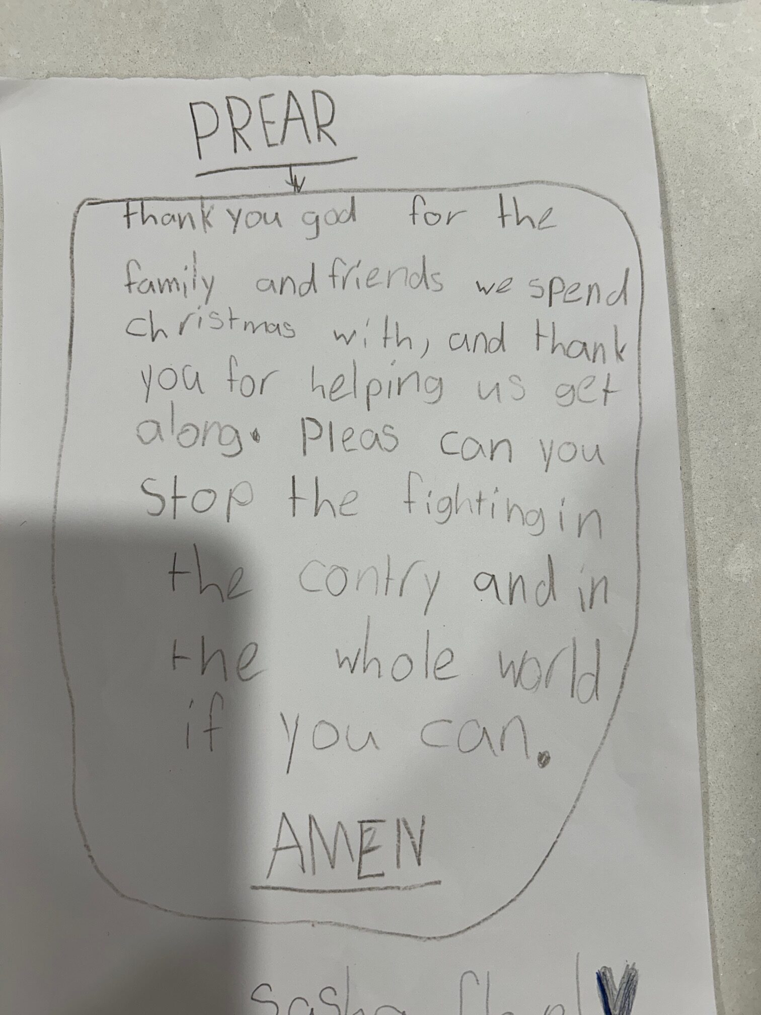 A piece of white paper with the following handwriting: PREAR: thank you god for the family and friends we spend Christmas with, and thank you for helping us get along. Pleas can you stop the fighting in the contry and in the whole world if you can. AMEN.