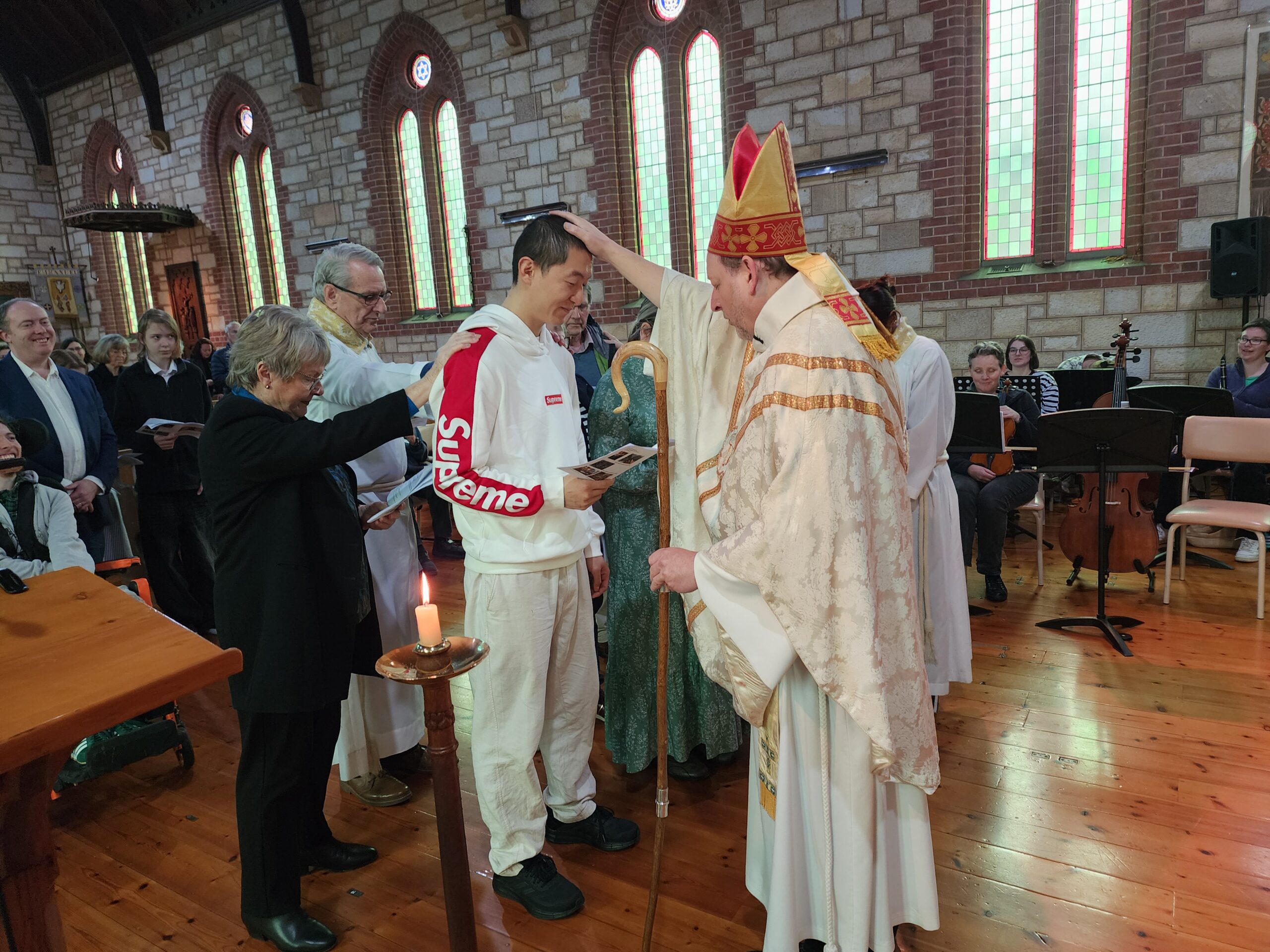 Archbishop places a hand on a man's head in a busy church.