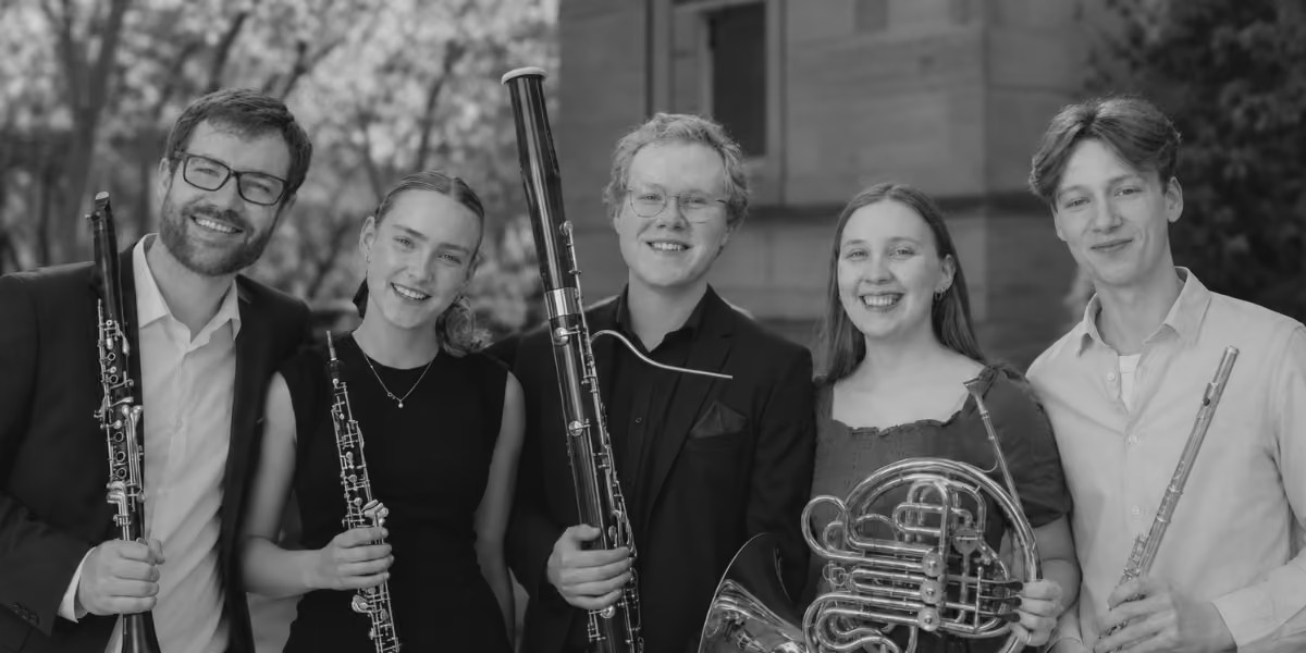 Black and white photo of five smiling musicians.