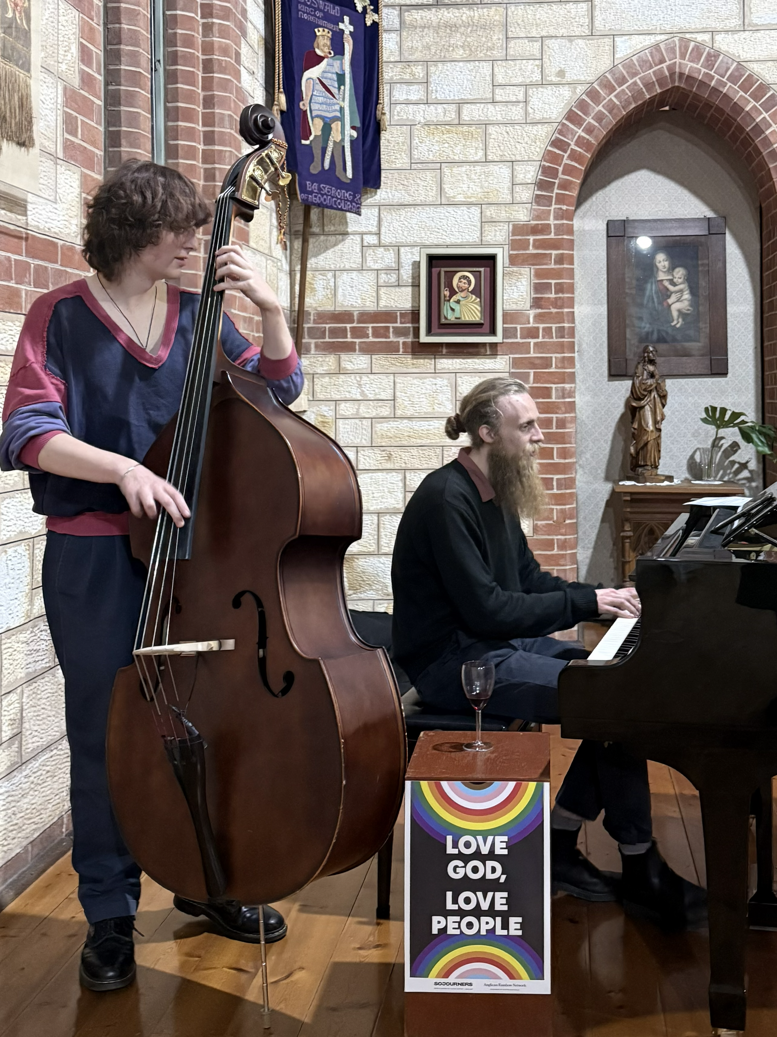 Two musicians in a church playing double bass and piano.